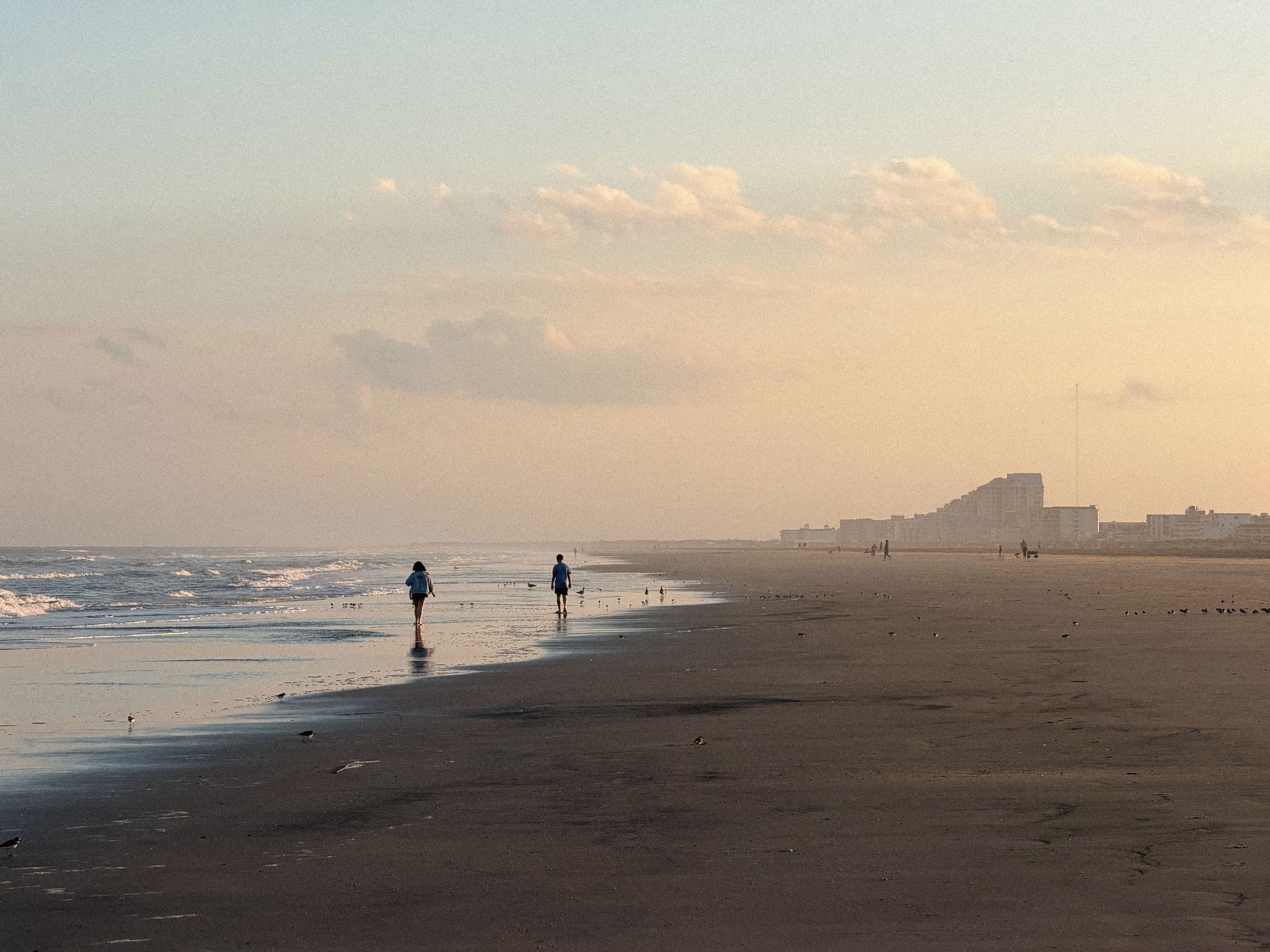 Two people walking the waterline at golden hour, Wildwood, NJ